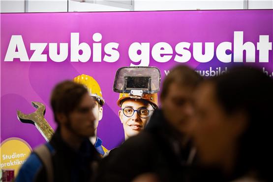 Besucher stehen auf der Jobmesse „KarriereStart“ vor dem Schriftzug „Azubis gesucht“. Foto: Sebastian Kahnert/dpa