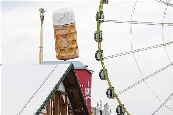 Ein Riesenrad ist auf dem Festgelände Cannstatter Wasen für das Frühlingsfest aufgebaut, im Vordergrund stehen Festzelte und ein überdimensionaler Bierkrug. Foto: Bernd Weißbrod/dpa