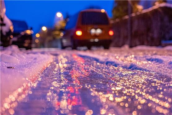 Eine dünne Eisschicht überzieht am frühen Morgen eine Straße. Foto: Armin Weigel/dpa/Symbolbild