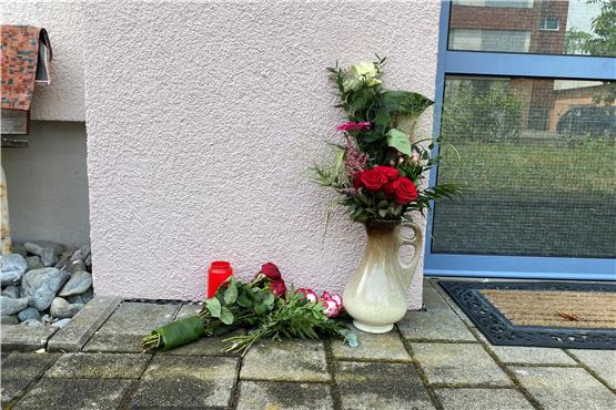 Vor dem Mehrfamilienhaus, in dem die getötete 22-Jährige lebte, haben Leute Blumen und eine Kerze abgelegt. Bild: Jacqueline Schreil