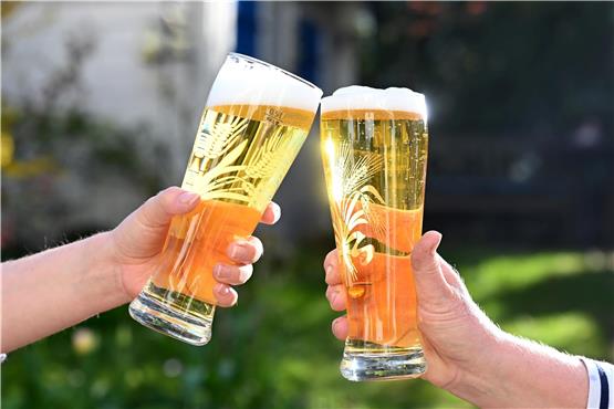 Zwei Personen stoßen mit Bier an. Foto: Bernd Weißbrod/dpa/Symbolbild