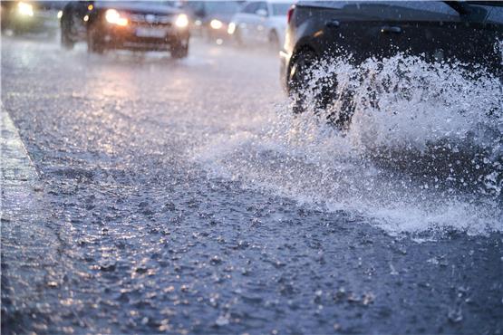Autos fahren bei starkem Regen durch tiefe Pfützen. Foto: Annette Riedl/dpa/Symbolbild