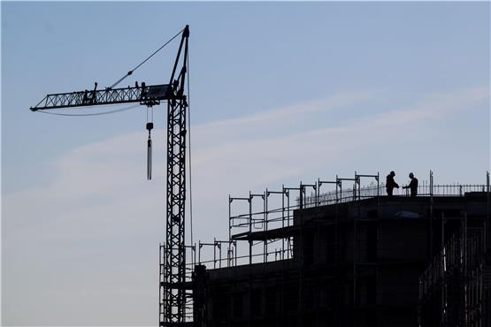 Bauarbeiter stehen auf der Baustelle eines Mehrfamilienhauses. Foto: Julian Stratenschulte/dpa/Symbolbild