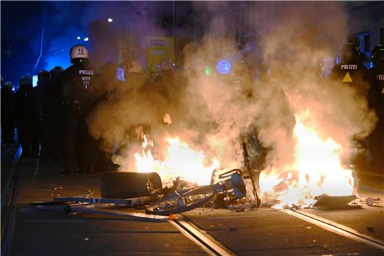 Bei den gewalttätigen Protesten in Leipzig stehen Polizisten hinter einer brennenden Barrikade.  Foto: Robert Michael/dpa