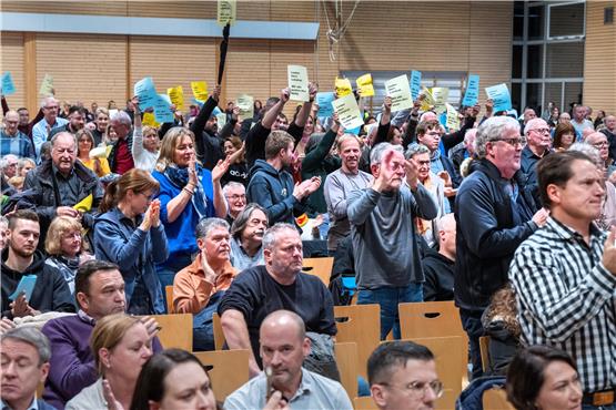 Bei der Bürgerversammlung hielten Teile des Publikums Zettel mit der Aufschrift „Lieber Herr Landrat, wir alle wollen dies nicht“ hoch. Bild: Klaus Franke