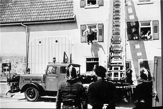 Beim Kreisfeuerwehrtag 1962 war es nur eine Übung, die diesen Mann veranlasste, ins Sprungtuch zu hüpfen. Um etwa 1905 brannte es hier tatsächlich. Nach einem Lageplan von 1903 standen in der Gartenstraße 2 (hier im Bild) und 4 zwei getrennte Wohnhäuser mit Scheunen. Ein Gebäude machte sich einst direkt im heutigen Einmündungsbereich der Brunnenstraße breit. Der Brand führte letztlich zum Neubau des heutigen Doppelhauses, auch „Wulle-Haus“ genannt.Die damals moderne Drehleiter gehörte der Tübinger Wehr. In Nehren ging es zu dieser Zeit darum, für die 12 Meter lange und 33 Jahre alte Magirus-Leiter eine Vorrichtung zu beschaffen, damit sie von einem Traktor gezogen werden konnte. Bild: Roland Schneider.