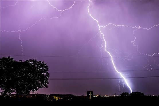 Blitze zucken während eines Gewitters am abendlichen Himmel. Foto: Christoph Schmidt/dpa