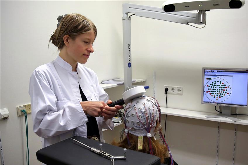 Brigitte Zrenner hält hier die Magnetspule an den mit EEG-Elektroden verkabelten Kopf der Probandin. Die Nervenzellen werden mit neuartiger Präzision stimuliert. Bild: Sommer