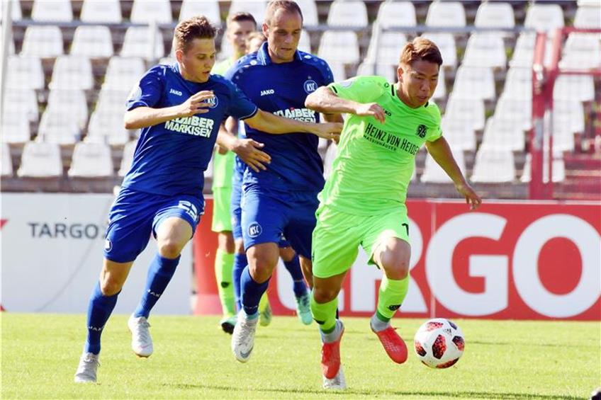 Der Hannoveraner Takumo Asano (r. Torschütze zum 0:4) kämpft mit den Karlsruher Janis Hanek (l) und Marco Thiede (M) um den Ball. Foto: Uli Deck dpa