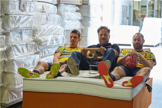 Der Schweizer Löwen-Kapitän Andy Schmid (links) und DHB-Nationalspieler Steffen Fäth (rechts) mit Röwa-Chef Manfred Greiner beim Dreh – auf einem Bett. Bild: Röwa