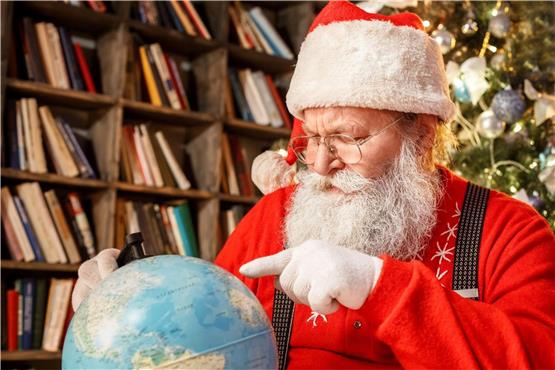 Der Weihnachtsmann sucht auf einer Weltkugel nach einem Ort.