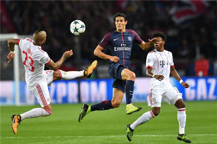 Die Bayern-Profis  Arturo Vidal (l.) und David Alaba (r.) bemühen sich um den Ball. Der lachende Dritte jedoch war Edinson Cavani von Paris St. Germain. Er erzielte den Treffer zum 2:0 für die Franzosen. Foto: afp