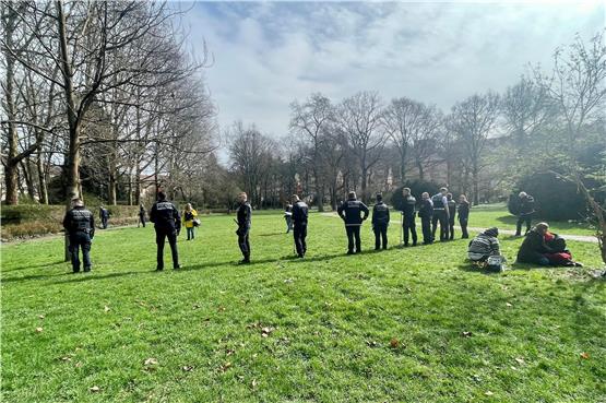 Die Polizei durchkämmt am Freitag den Alten Botanischer Garten. Rechts sitzen die trauernden Freunde des Opfers. Bild: Jonas Bleeser
