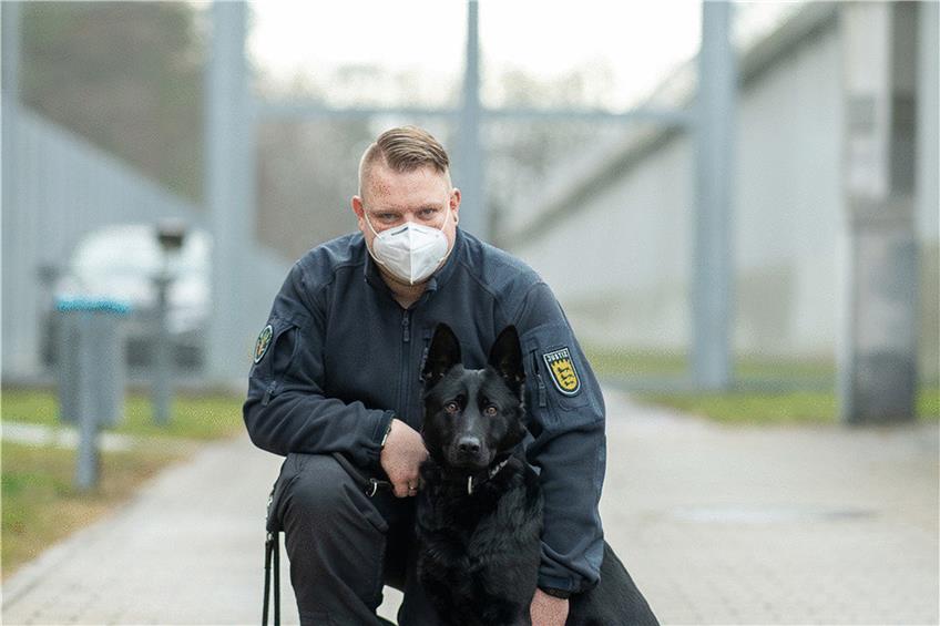 Diensthundeführer Florian Weiner steht mit seiner schwarzen Schäferhündin Emily, einem Spürhund für Handys, vor der JVA Heimsheim.  Foto: Sebastian Gollnow/dpa