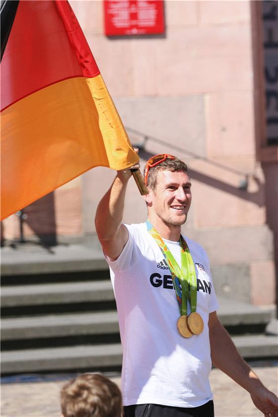 Doppel-Olympiasieger Sebastian Brendel schwingt bei der Ankunft stolz die deutsche Fahne. Foto: Eibner