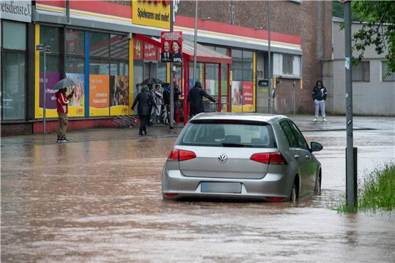 Ein Auto fährt durch das Hochwasser in einer Saarbrücker Straße.