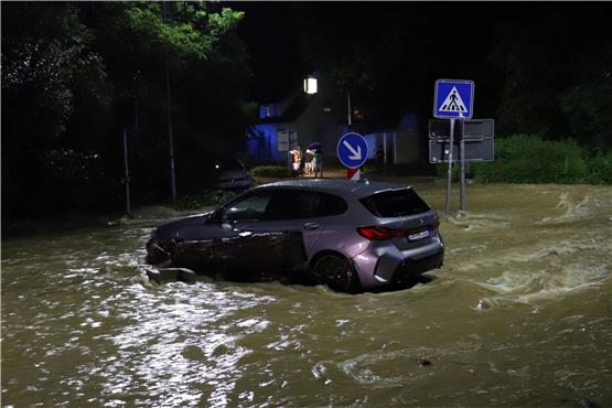 Ein Auto steht auf einer überfluteten Straße. Foto: Christian Wiediger/dpa