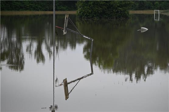 Ein Basketballkorb spiegelt sich im überschwemmten Sportplatz. Foto: dpa