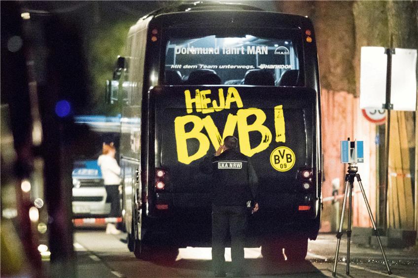 Ein Beamter untersucht den BVB-Mannschaftsbus. Foto: Marcel Kusch/dpa