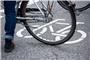 Ein Fahrrad-Symbol ist auf der Fahrbahn einer Straße hinter einem Fahrrad zu sehen. Foto: Jonas Walzberg/dpa/Symbolbild