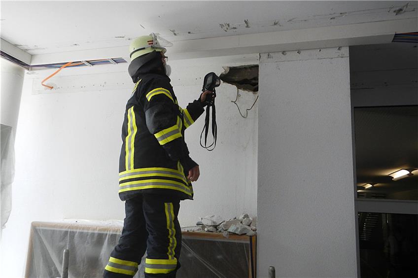 Ein Feuerwehrmann kontrolliert mit einer Wärmebildkamera die Wand im Firstwaldgymnasium. Bild: Mario Beißwenger