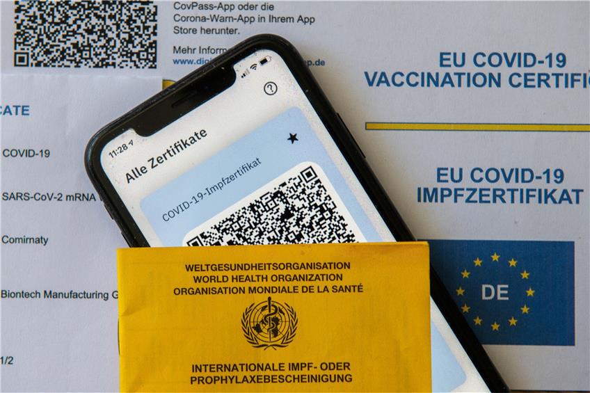 Ein Impfpass und ein Smartphone, auf dem die App CovPass läuft, liegen auf einem Impfzertifikat, das von einer Apotheke ausgestellt wurde. Foto: Stefan Puchner/dpa