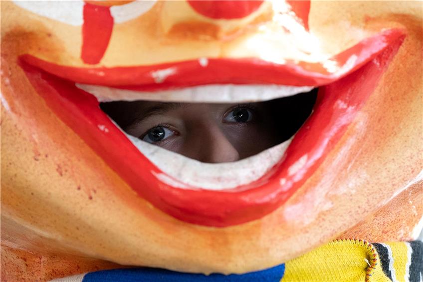 Ein Junge schaut aus dem Mund eines Kinder-Schwellkopps, also eines übergroßen Karikaturenkopfs. Foto: Sebastian Gollnow/dpa/Symbolbild