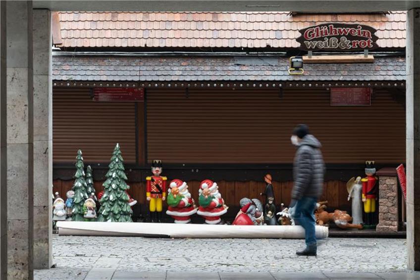 Ein Mann geht an einer Weihnachtsmarktsbude vorbei. Foto: Marijan Murat/dpa/Archivbild