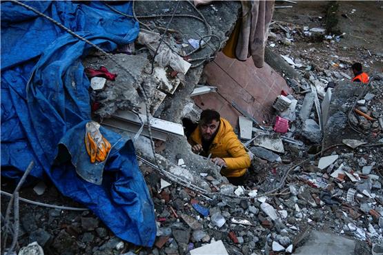 Ein Mann in Adana sucht nach Verschütteten in den Trümmern eines zerstörten Gebäudes. Foto: Khalil Hamra/AP/dpa