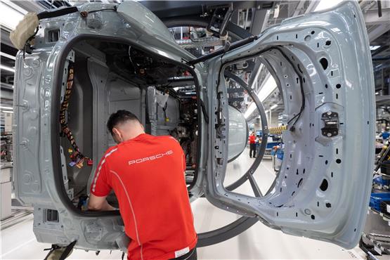 Ein Mitarbeiter der Porsche AG montiert im Stammwerk in Zuffenhausen einen vollelektrischen Porsche Taycan. Foto: Marijan Murat/dpa