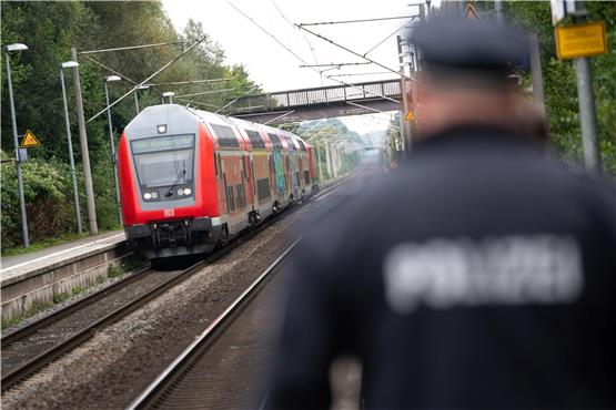Ein Polizist läuft über einen Bahnsteig während im Hintergrund ein doppelstöckiger Regionalzug einfährt. Foto: Jonas Walzberg/dpa