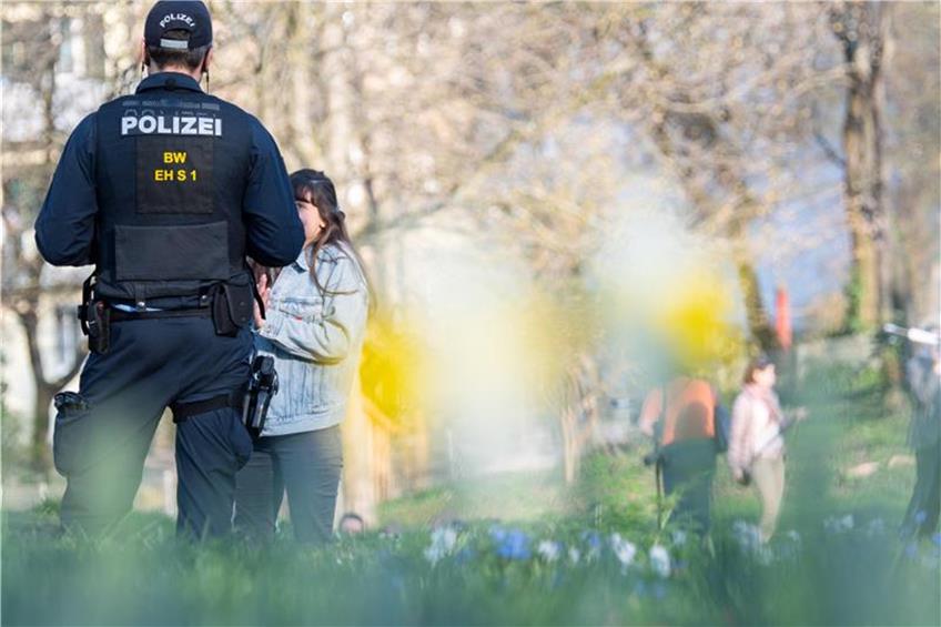 Ein Polizist spricht in einem Park eine Frau an. Foto: Sebastian Gollnow/dpa/Archivbild