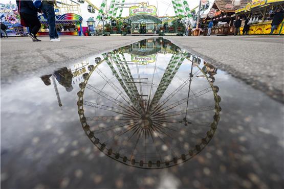 Ein Riesenrad spiegelt sich in einer Pfütze auf dem Festgelände des Stuttgarter Frühlingsfestes. Foto: Marijan Murat/dpa