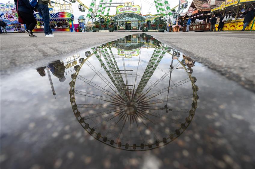 Ein Riesenrad spiegelt sich in einer Pfütze auf dem Festgelände des Stuttgarter Frühlingsfestes. Foto: Marijan Murat/dpa