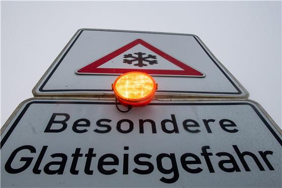Ein Straßenschild warnt mit einer Blinkleuchte vor Glatteis. Foto: Stefan Puchner/dpa/Symbolbild
