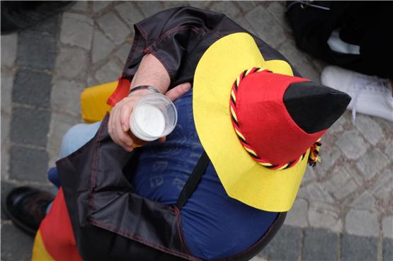 Ein Teilnehmer des Public Viewings hält während eines Deutschland-Spiels ein Bier in der Hand. Foto: Sebastian Willnow/dpa-Zentralbild/dpa/Symbolbild