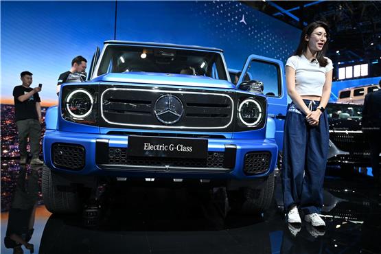 Eine Frau steht vor einer Mercedes G-Klasse auf der Automesse in China. Foto: Johannes Neudecker/dpa