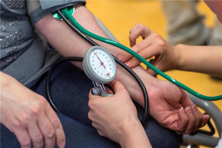 Eine Pflegekraftmesst bei einer Frau den Blutdruck. Foto: Jens Büttner/Archiv dpa/lsw