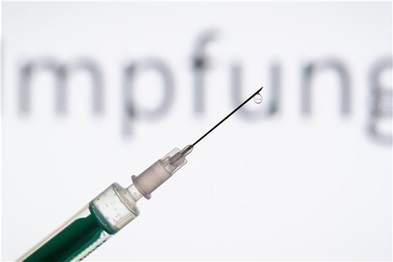 Eine Spritze wird vor den Schriftzug „Impfung“ gehalten. Foto: Friso Gentsch/dpa/Symbolbild