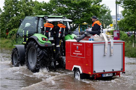 Feuerwehrleute fahren über einer überflutete Straße. Foto: Sven Hoppe/dpa