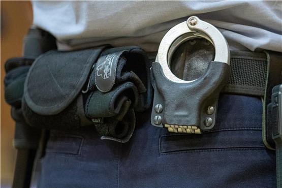 Handschellen stecken in der Gürtelhalterung eines Justizbeamten. Foto: Friso Gentsch/dpa/Symbolbild