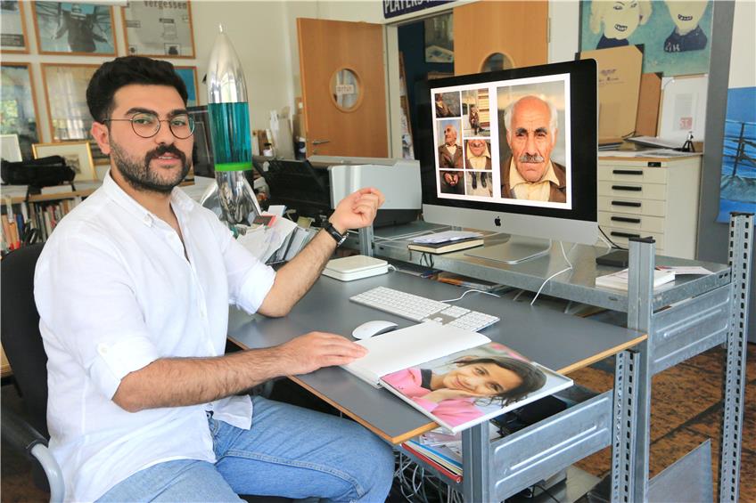 Hasan Malla mit Fotos seiner Abschlussarbeit als Grafik-Designer. Bild: Manfred Hantke