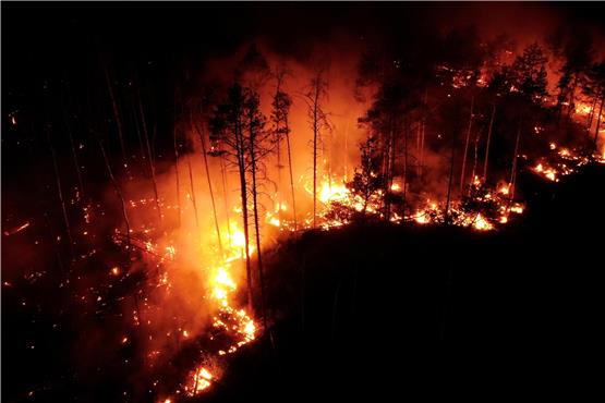 In Jüterbog (Brandenburg) schlagen bei Nacht in einem Wald Flammen in die Höhe (Aufnahme mit Drohne). Foto: Thomas Schulz/dpa