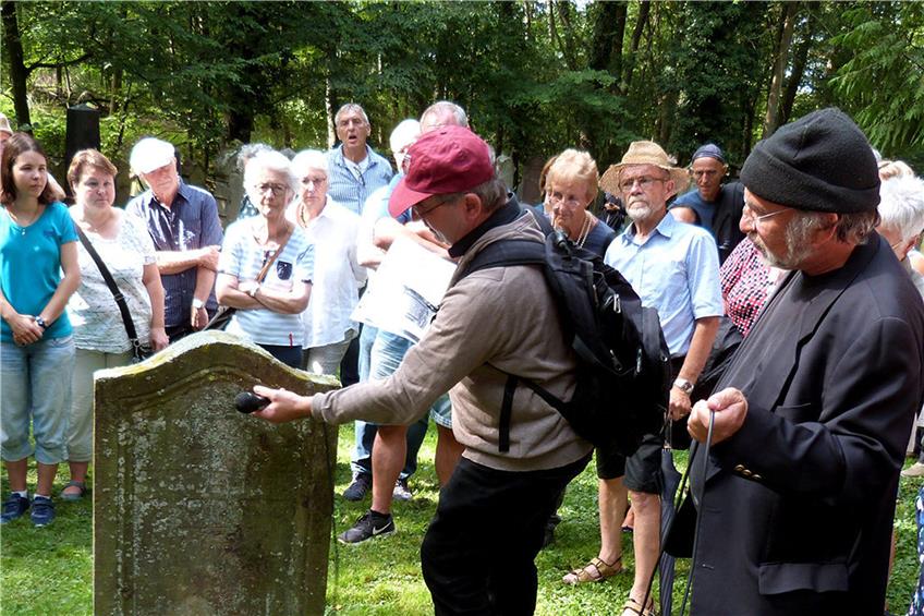Martin Ulmer (mit roter Mütze) erklärt die Inschrift eines Grabsteins auf dem jüdischen Friedhof. Bild: Werner Bauknecht