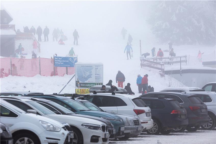 Menschen stehen im Nebel nahe dem Skilift am Haldenköpfle. Im Vordergrund der volle Parkplatz der geschlossenen Liftanlage.  Foto: Philipp von Ditfurth/dpa