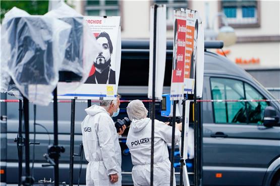 Mitarbeiter der Spurensicherung stehen auf dem Marktplatz an einem Stand neben Plakaten. Foto: Uwe Anspach/dpa