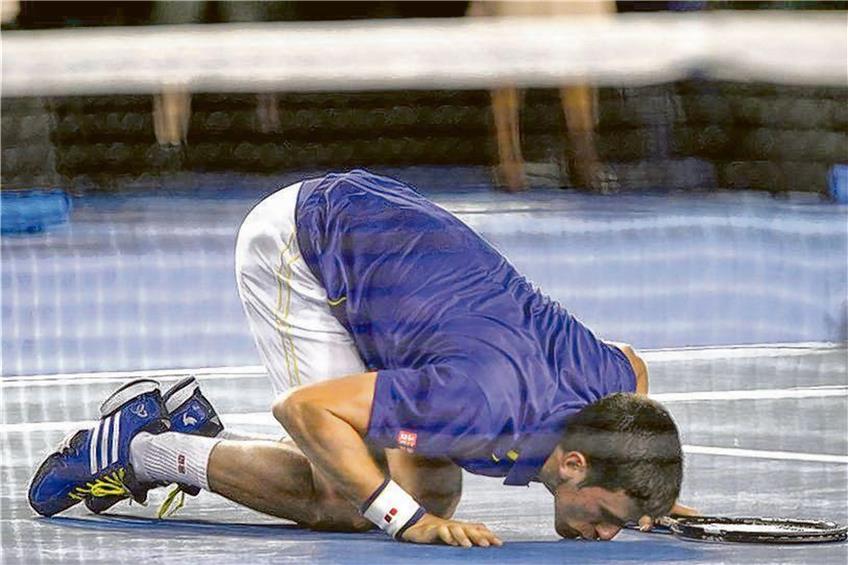 Novak Djokovic ist stolz auf seinen sechsten Grand-Slam-Sieg und küsst den glückbringenden Centercourt der Rod-Laver-Arena. Foto: Actionpress