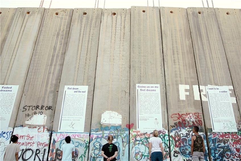 Palästinensische und deutsche Jugendliche vor einer Mauer zwischen Israel und dem Westjordanland. Bild: Verleih