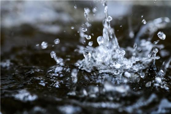 Regentropfen fallen während eines Schauers in eine Wassertonne. Foto: Robert Michael/dpa