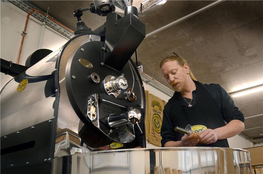 Sind die Bohnen fertig geröstet? Florian Kühnberger an seiner Röstmaschine mit strengem Blick auf den Probenzieher. Bild: Rippmann